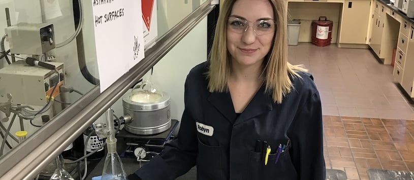 A student in a lab coat who went through the online Office Administration program