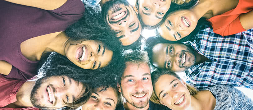 Group of young adults looking downward and smiling.